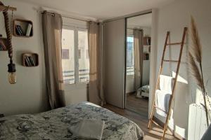 Schlafzimmer mit einem Bett, einer Leiter und einem Spiegel in der Unterkunft Bel appartement sur le port du Brusc avec sa place de parking privative. in Six-Fours-les-Plages