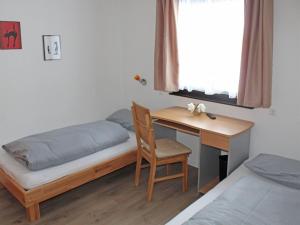 um quarto com uma secretária e uma cama e uma secretária com uma cadeira em Ferienhaus Nr 12, Kategorie Komfort, Feriendorf Hochbergle, Allgäu em Bichel
