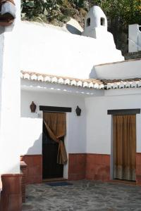 un edificio blanco con una puerta con cortina en Casa Cueva Sierra Nevada - Monachil, en Monachil