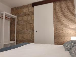 a bedroom with a white bed and a brick wall at Casa de la Escalera in Córdoba