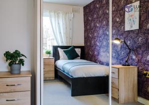 ein Schlafzimmer mit einem Bett und einer lila Wand in der Unterkunft Luke Stays - John Hunter Way in Sefton