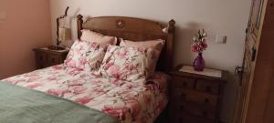 a bed with pink floral sheets and a vase of flowers at Casa da Tileira in Penacova