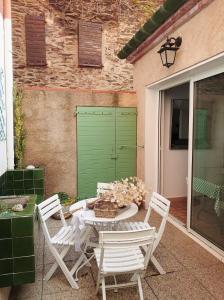 a patio with a table and chairs and a green door at 6EGA14 Superbe maison Familiale 6 personnes in Collioure