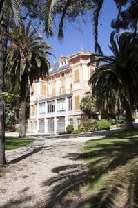 a large white building with palm trees in front of it at Narciso Centralissimo in Sanremo