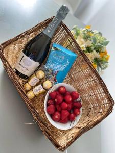 a basket with a bottle of wine and a bowl of berries at Dympna's City Centre apartment, Armagh in Armagh
