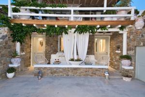 an outdoor patio with a white bench and plants at Mykonos Dot in Ano Mera