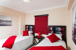 two beds in a room with red and white at Pebble Beach 26 in Ballito