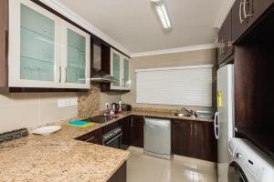 a large kitchen with wooden cabinets and a dishwasher at Pebble Beach 26 in Ballito