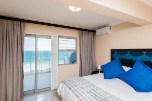 a bedroom with a bed with blue pillows at Pebble Beach 26 in Ballito