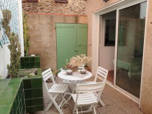 a table and chairs on a patio with a green door at 6EGA14 Superbe maison Familiale 6 personnes in Collioure