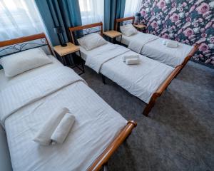 three beds in a room with towels on them at Kelman Inn Global Nowa Sól in Nowa Sól