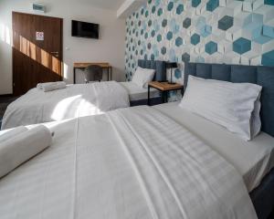 two beds in a hotel room with white sheets at Kelman Inn Global Nowa Sól in Nowa Sól