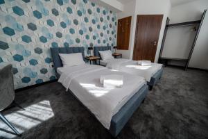 two beds in a room with blue and gray wallpaper at Kelman Inn Global Nowa Sól in Nowa Sól