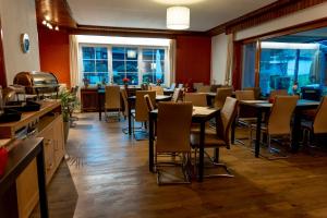 a dining room with tables and chairs and windows at Hotel Tiefenhagen Sauerland in Lennestadt
