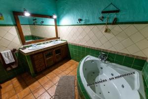 een badkamer met een bad, een wastafel en een spiegel bij Casa Rural Abuelo Ramón in Vallehermoso