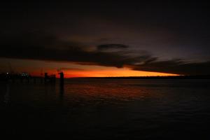 a sunset over a body of water with a pier at Matildas End Holiday Units in Karumba