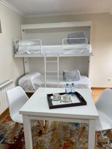 Zimmer mit einem Tisch, Stühlen und Etagenbetten in der Unterkunft O SECRETO in Padrón