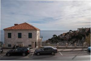 due auto parcheggiate in un parcheggio accanto a un edificio di Apartment Pulastar a Dubrovnik