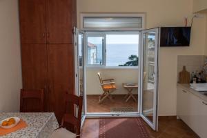a kitchen with a sliding glass door with a view of the ocean at Apartment Pulastar in Dubrovnik