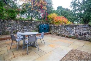 un patio con mesa, sillas y pared de piedra. en Meath Arms Country Inn, en Aughrim