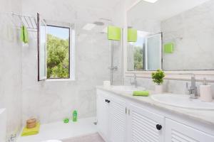 a white bathroom with two sinks and a mirror at Villa Marisol in Sant Lluis
