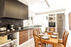 a kitchen with a wooden table with chairs and a dining room at Villa Marisol in Sant Lluis