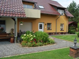 una casa gialla con un giardino fiorito di fronte di Pension + Apartments Tor zum Spreewald a Lübben