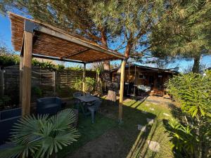 a backyard with a wooden pergola and a table and chairs at La cabane de Carol au coeur du bassin d'Arcachon in Le Teich