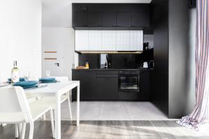 a kitchen with black cabinets and a white table and chairs at Deluxe Apartments Sucha Gdańsk by Renters in Gdańsk
