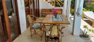 a wooden table with a vase of flowers on a porch at MOYO apartment in Pwani Mchangani