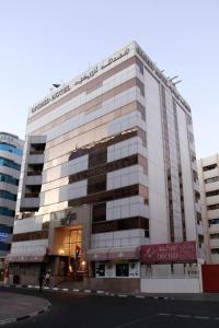 a large white building on the corner of a street at Orchid Hotel in Dubai