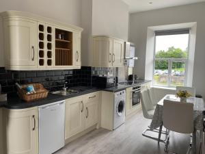 a kitchen with white cabinets and a sink and a dishwasher at Dympna's City Centre apartment, Armagh in Armagh