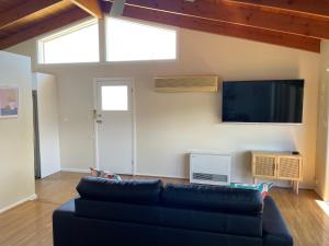 a living room with a black couch and a flat screen tv at Close to Coast & Bellarine Peninsula in Moolap
