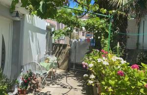 a garden with flowers and a chair on a patio at Apartman Annamaria in Cres