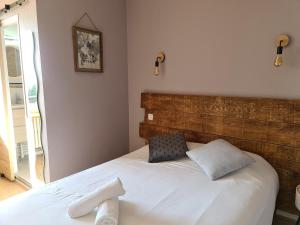 QueyracにあるHotel Les Vieux Acaciasの白いベッド1台(木製ヘッドボード付)が備わるベッドルーム1室が備わります。