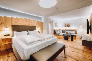 um quarto com uma grande cama branca e um sofá em Obermühle 4*S Boutique Resort em Garmisch-Partenkirchen