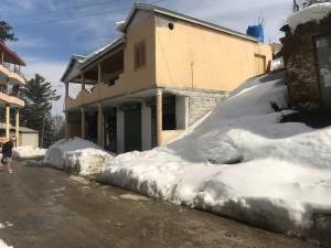 a pile of snow in front of a building at ViveGee Cottage Khanipur Ayubia in Ayubia