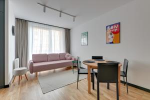 uma sala de estar com um sofá rosa e uma mesa em Downtown Apartments Dwie Motławy Riverside & Parking em Gdansk