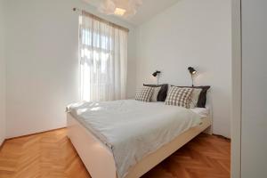 ein weißes Schlafzimmer mit einem Bett und einem Fenster in der Unterkunft Apartment Tin in Trogir