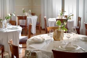 un comedor con mesas y sillas blancas y manteles blancos en Terme Preistoriche Resort & Spa, en Montegrotto Terme