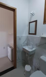 a bathroom with a sink and a toilet and a mirror at Ilha Suites - Vila do Abraão in Abraão