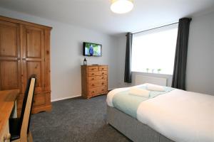 
a bedroom with a bed and a television at Central Serviced Apartments by Roomsbooked in Cheltenham
