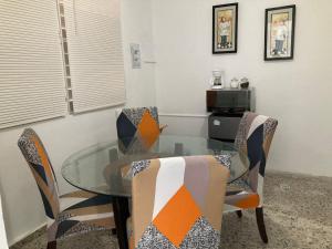 a dining room with a glass table and chairs at The Little Blue House in Guayama