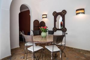 une table avec des chaises et un vase avec des fleurs. dans l'établissement Riad Al Tainam, à Marrakech