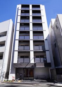 a tall white apartment building with a parking lot at SG Residence Inn Hakataekiminami in Fukuoka