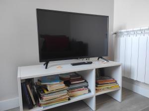 TV de pantalla plana en un puesto blanco con libros en La Portela Riverside, en Redondela