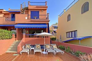 eine Terrasse mit Stühlen und einem Sonnenschirm vor einem Gebäude in der Unterkunft Bahía Meloneras 71 in Meloneras