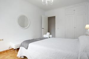 ein weißes Schlafzimmer mit einem weißen Bett und einem Spiegel in der Unterkunft Casa Pedro in Conil de la Frontera