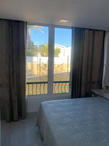 ein Schlafzimmer mit einem Bett und einem großen Fenster in der Unterkunft CASA ME ENCANTA in Playa de las Americas