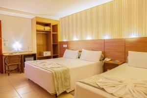 a hotel room with two beds and a desk at Amazon Plaza Hotel in Cuiabá